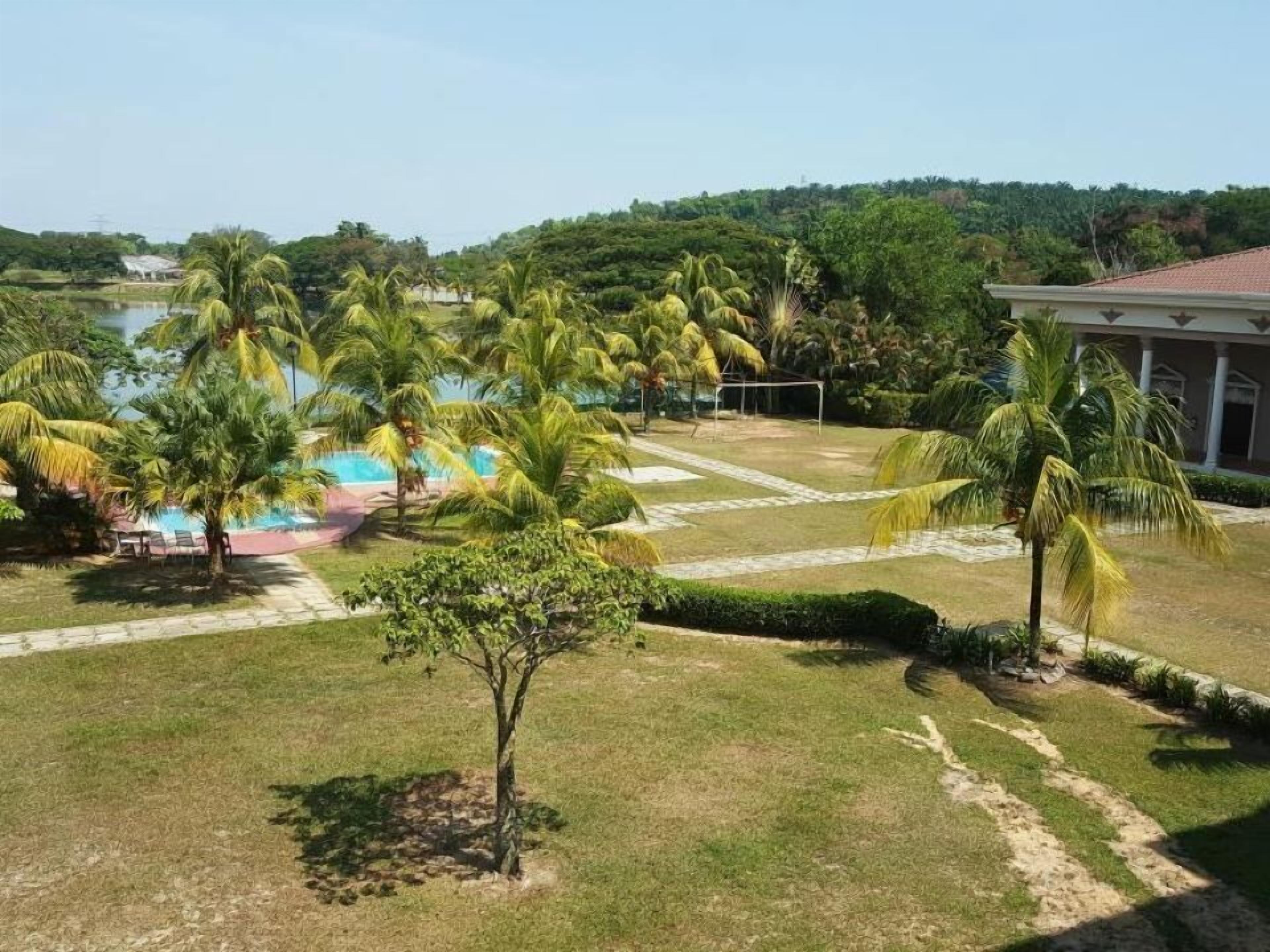 A pool area with palm trees, a building with columns, and a view of a hill.