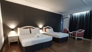A hotel room with two beds, a nightstand, a chair, and a window with curtains. - Hotel Seri Malaysia Kulim (Kulim)