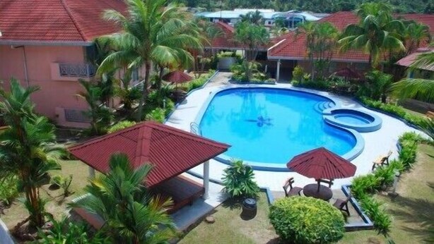 Una piscina rodeada de palmeras y edificios con tejados rojos.