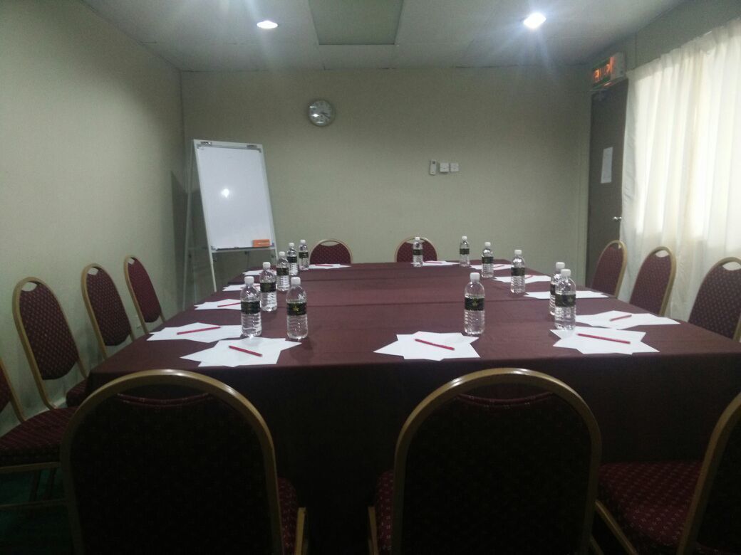 Une salle de conférence avec une longue table, des chaises, un tableau blanc et une horloge au mur.