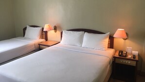 Habitación de hotel con dos camas individuales, cada una con mesita de noche, lámpara y teléfono.