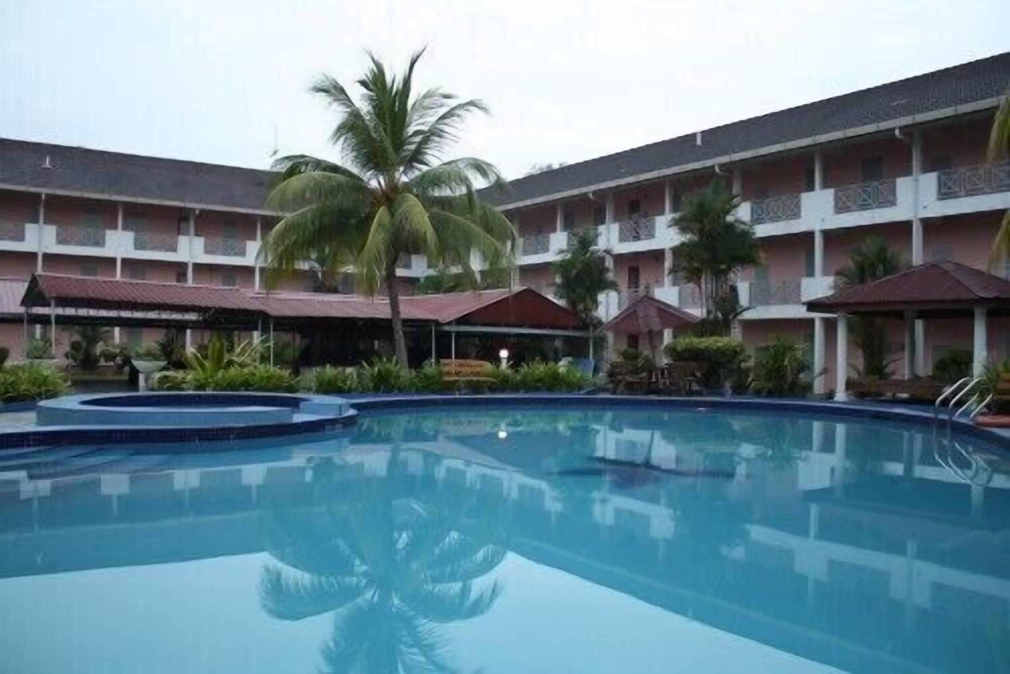 A swimming pool with a palm tree in the center, surrounded by a multi-story building with balconies.