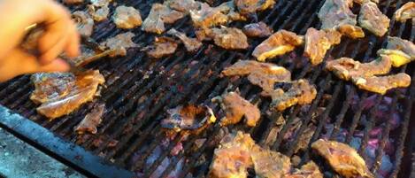 Una parrilla con varios tipos de carne asándose.