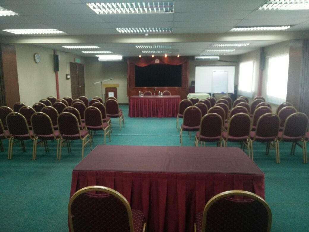 A conference room with rows of chairs, a stage, and a whiteboard.