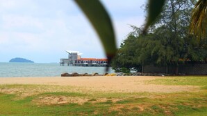 A beach view with a building on stilts over the water, a sandy shore, and some greenery. - Hotel Seri Malaysia Port Dickson (Port Dickson)