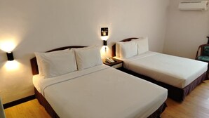 A hotel room with two single beds, a nightstand with a phone, a wall-mounted air conditioner, and a wooden floor. - Hotel Seri Malaysia Port Dickson (Port Dickson)