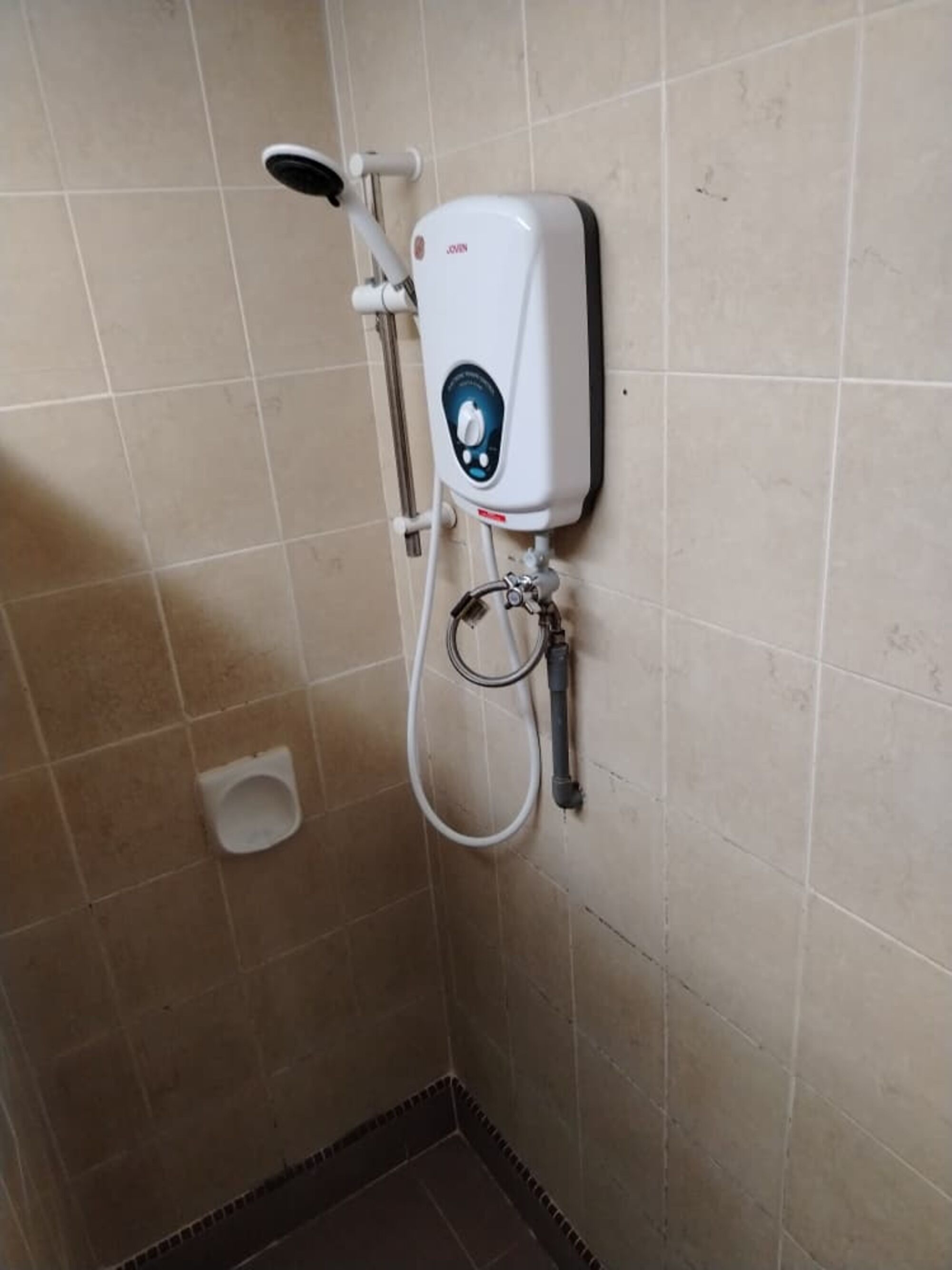 A shower with a handheld showerhead and a wall-mounted control panel.