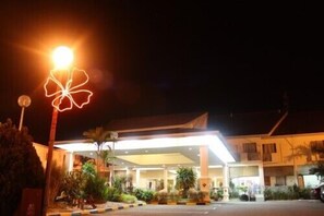 Entrada de hotel con un toldo bien iluminado y un aplique decorativo.