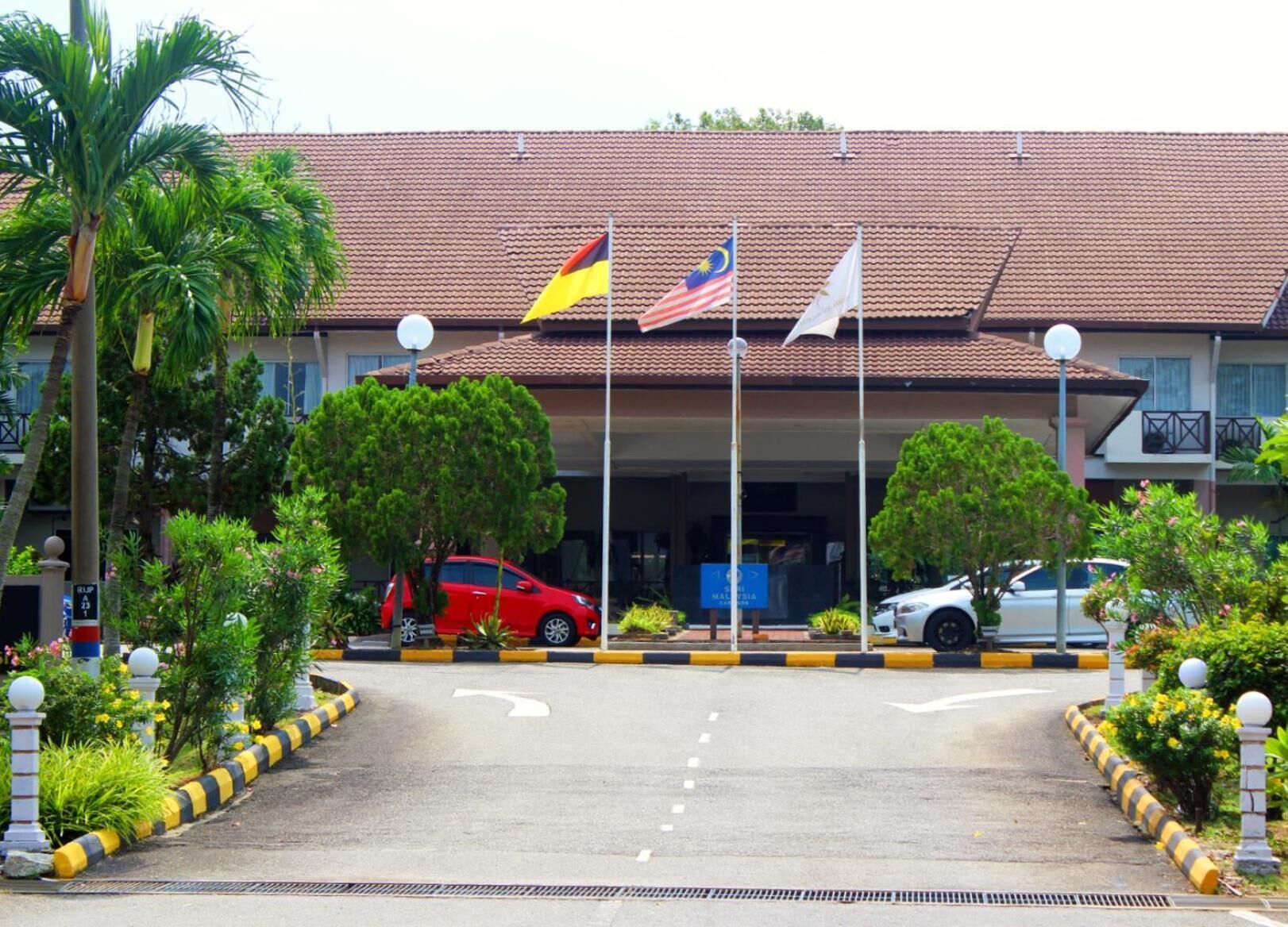 A building with a tiled roof, multiple flags, and a parking area with cars.