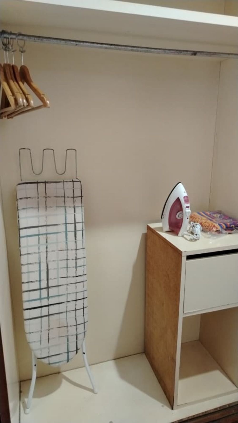 A small laundry area with a drying rack, an iron, and a wooden cabinet.