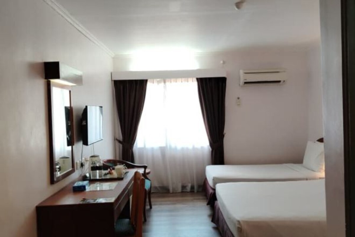Une chambre d’hôtel équipée d’un bureau, de deux lits, d’une télévision et d’un appareil de climatisation.