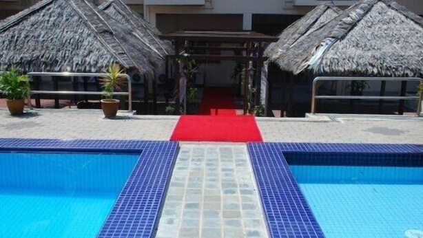 A swimming pool with a red carpet leading to a covered area with thatched roofs. - Hotel Seri Malaysia Port Dickson (Port Dickson)