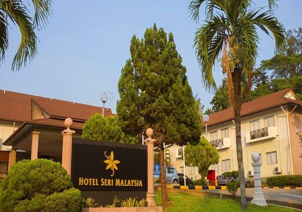 Schild für das Hotel Seri Malaysia mit freiem Blick auf den Haupteingang, Palmen und einem gepflegten Rasen.