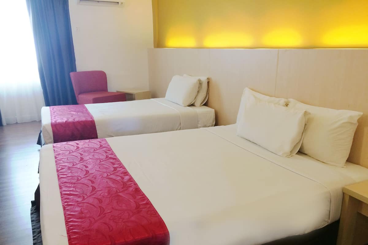 Une chambre d’hôtel avec deux lits, chacun recouvert d’une couverture rouge et blanche, et une seule chaise.
