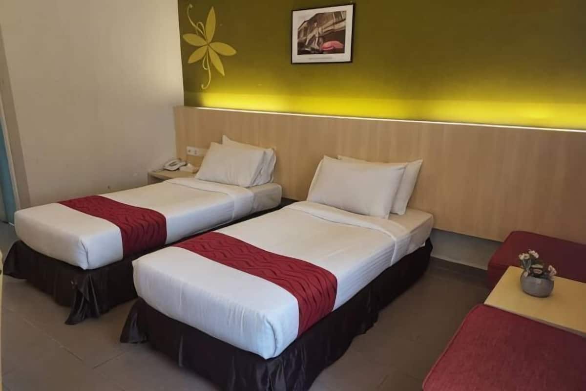 Une chambre d’hôtel avec deux lits simples, une petite table, une table de chevet et un téléphone fixé au mur.