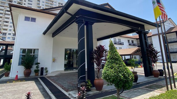 A hotel entrance with a covered patio, potted plants, and a flagpole with flags. - Hotel Seri Malaysia Pulau Pinang (George Town)