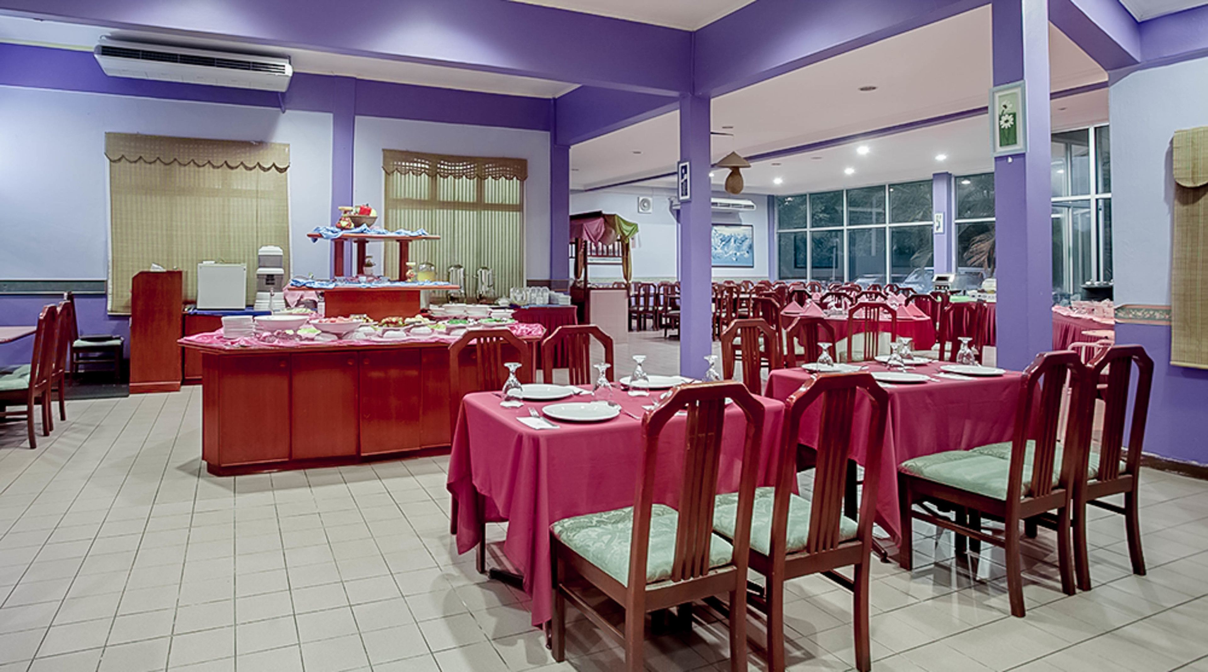 Un espace repas avec plusieurs tables dressées pour le service, et un buffet central proposant une variété de plats.