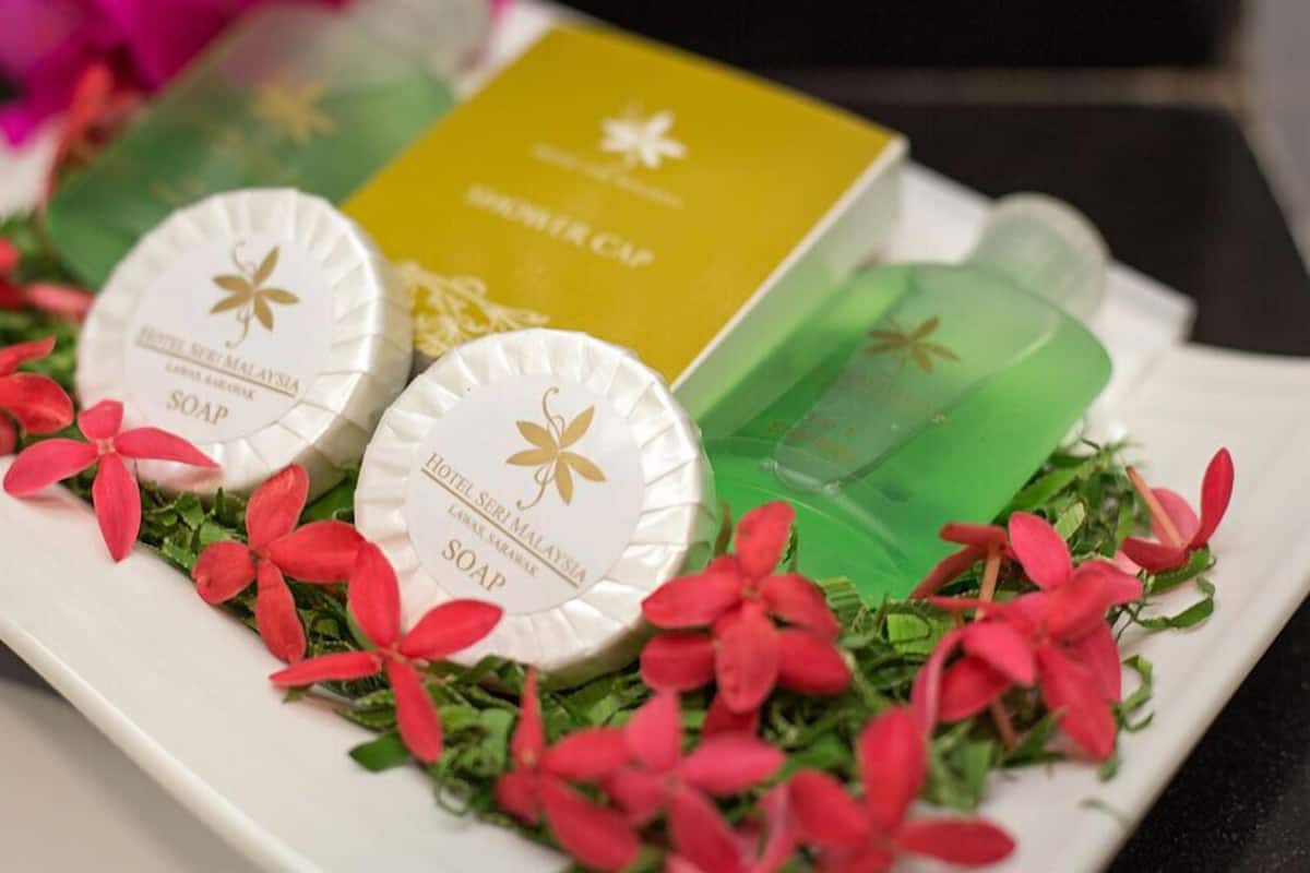 A tray with soap bars and a soap dispenser, surrounded by red flowers and greenery.