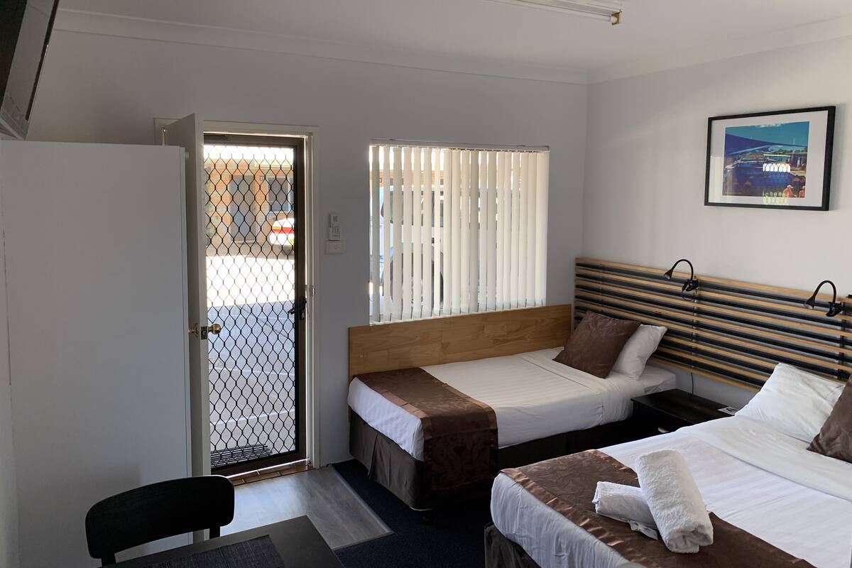 A hotel room with two beds, a desk, and a chair.