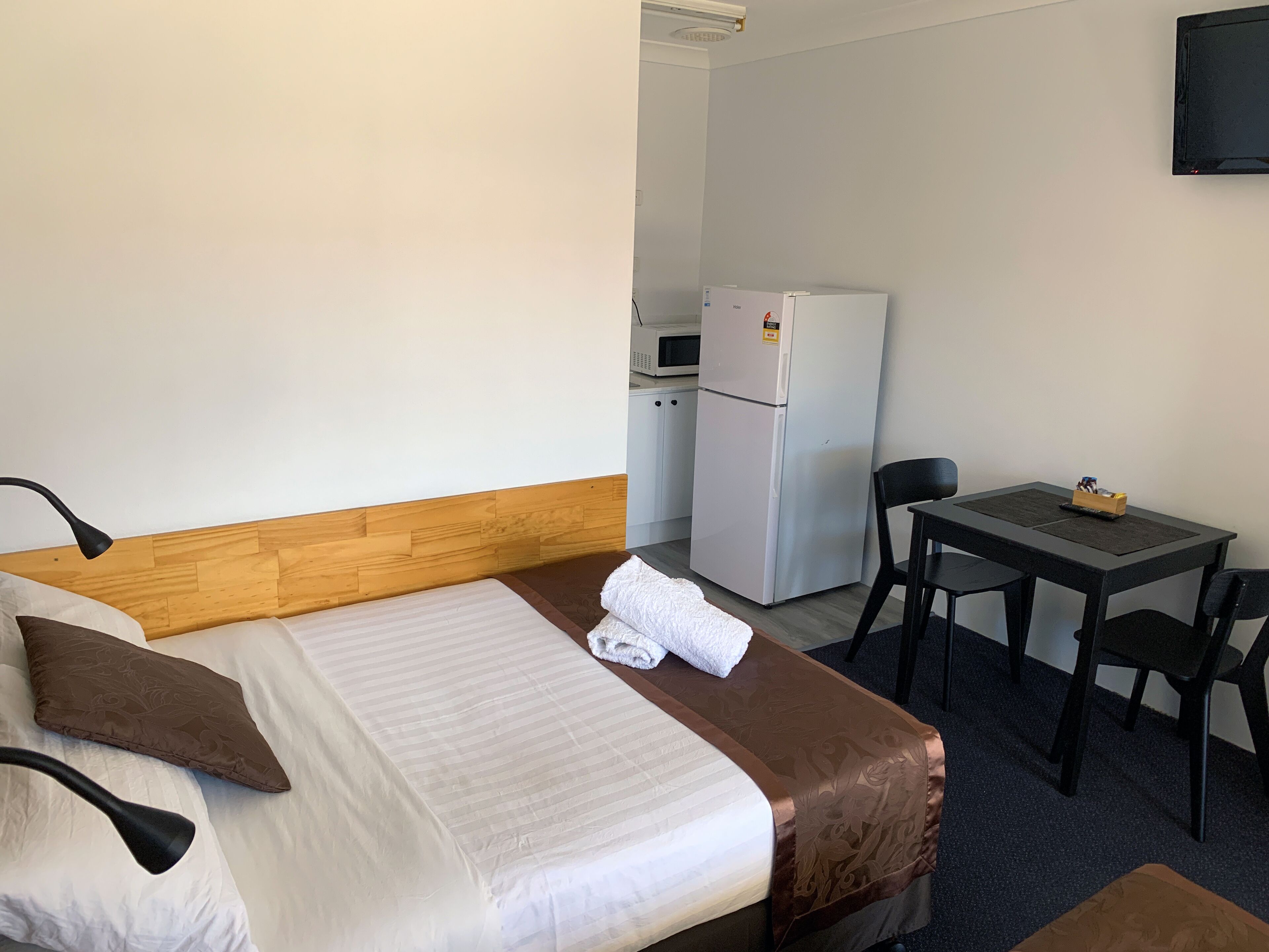 Ein Hotelzimmer mit Bett, Schreibtisch, Stuhl, Kühlschrank und Mikrowelle.