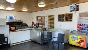 A restaurant interior with a counter, seating area, and ice cream display. - Baths Motel (Moree)