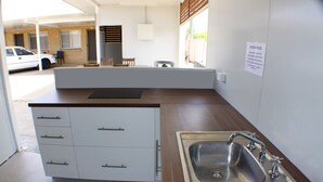 A compact kitchen with a built-in sink, a countertop, and a small dining area with chairs. - Baths Motel (Moree)