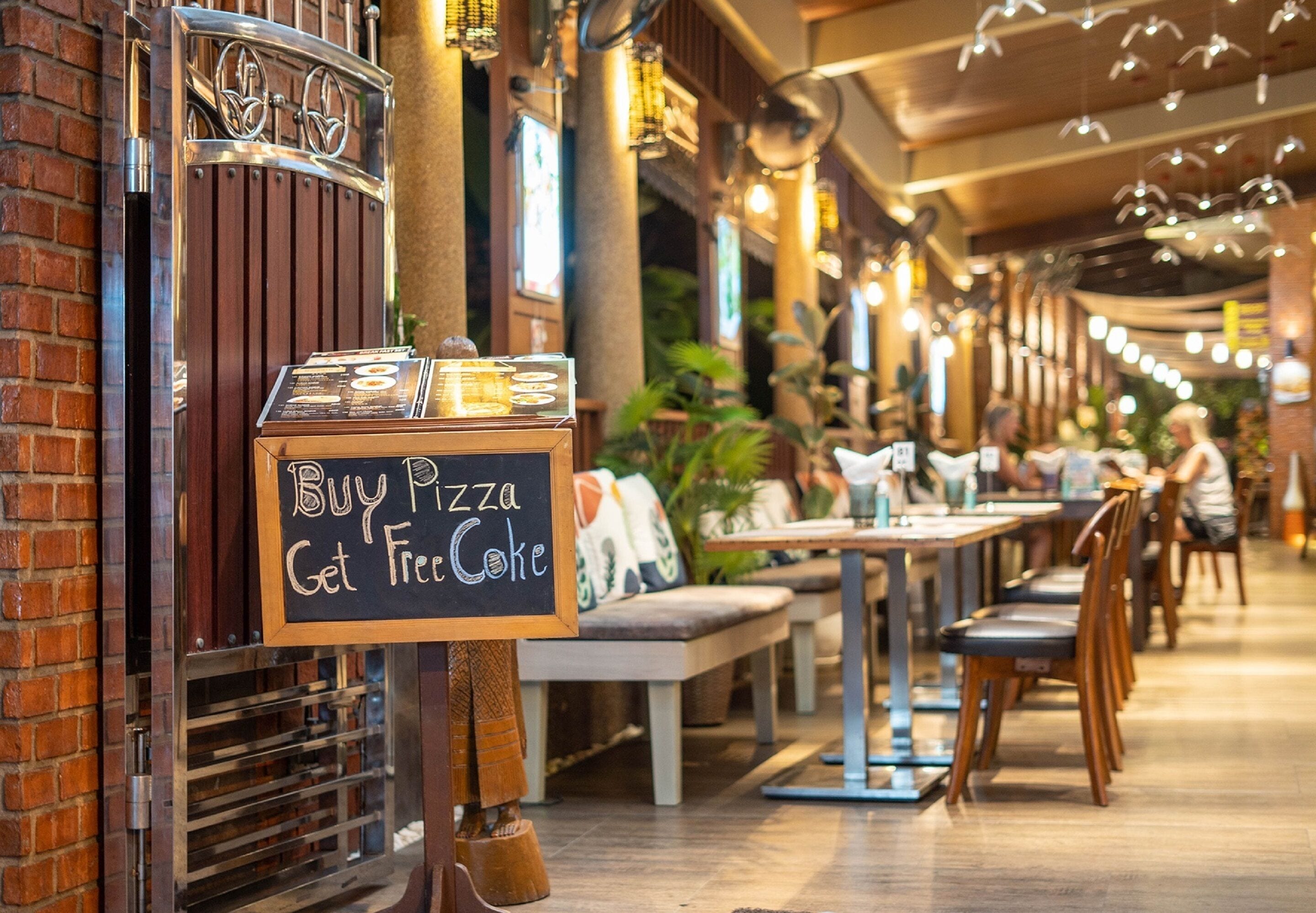 A restaurant interior with a sign offering a buy pizza get free coke deal.