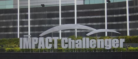A sign with the words "IMPACT Challenger" in front of a modern building with reflective windows.