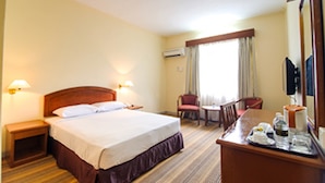A hotel room with a bed, bedside tables, a desk with a chair, a television, and a window with curtains. - Hotel Seri Malaysia Seremban (Seremban)