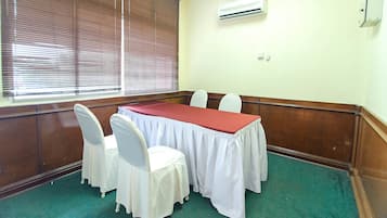 A conference room with a long table, white chairs, and a red tablecloth.