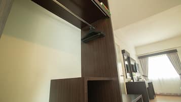 A modern living room with a dark wooden entertainment unit, a flat-screen TV mounted above it, and a large window with curtains.