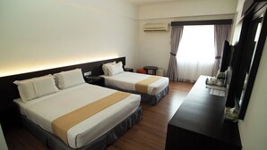 A hotel room with two beds, a desk, a chair, an air conditioning unit, and a television.