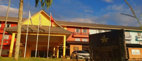 Entrada de un hotel con un área techada, un automóvil estacionado y un cartel que indica Hotel Seri Malaysia Sungai Petani.