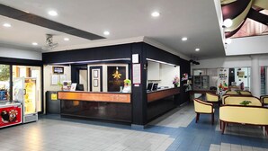 A hotel reception area with a black and white color scheme, a reception desk, and a seating area with yellow chairs.