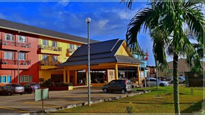 A multi-story hotel with balconies, a covered entrance, and a parking area.