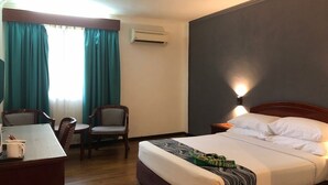 A hotel room with a bed, a desk with chairs, an air conditioner, and a window with curtains. - Hotel Seri Malaysia Taiping (Taiping)