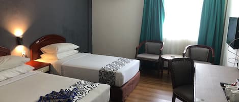 A hotel room with two beds, a desk, a chair, and an air conditioning unit.