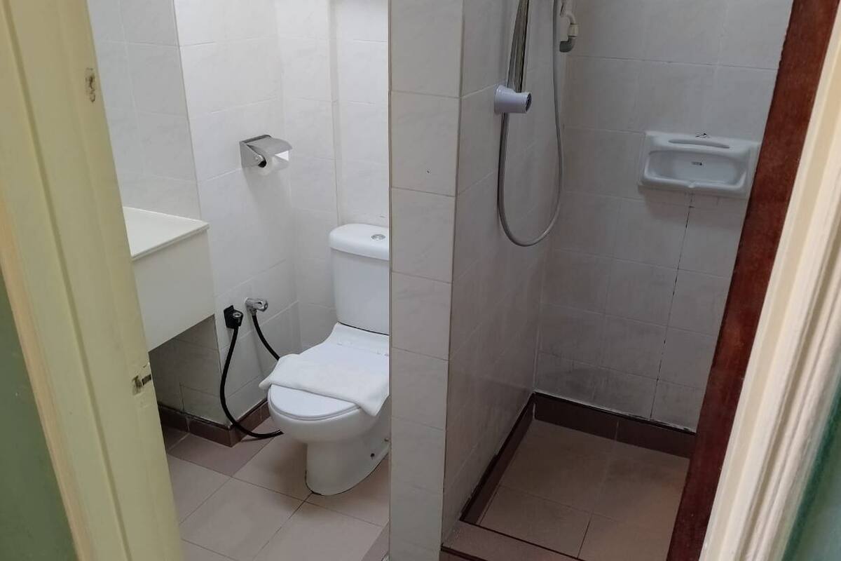 A small bathroom with a toilet, a shower, and a sink.