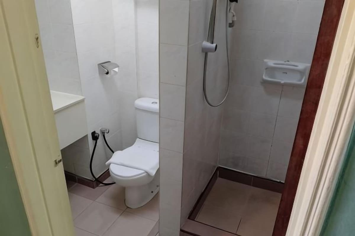A small bathroom with a toilet, a shower, and a sink.