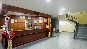 A reception area with a wooden counter, framed certificates, a trash bin, and a staircase. - Hotel Seri Malaysia Temerloh (Temerloh)