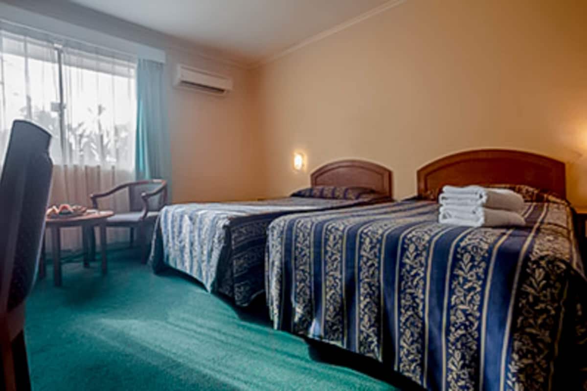 A hotel room with two beds, a desk, and a chair.