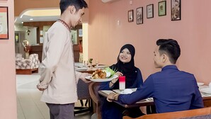 A dining area with a waiter serving food to two seated guests. - Hotel Seri Malaysia Temerloh (Temerloh)