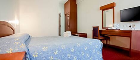A hotel room with a bed, a desk, a chair, a television, and a mirror.