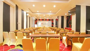 A conference room with rows of yellow chairs and tables, a whiteboard, and a red carpet. - Swiss-Belcourt Makassar (Makassar)