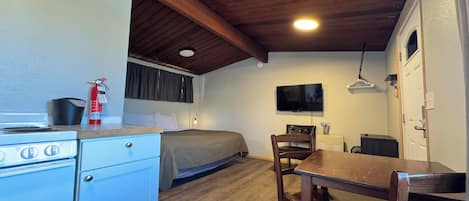 Una camera compatta con angolo cottura, un letto, una TV e un'area pranzo.