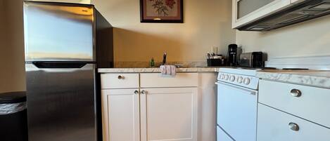 A kitchen with a stainless steel refrigerator, white cabinets, a microwave, and a stove.
