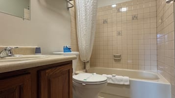 Casa de banho com sanita, lavatório e banheira.