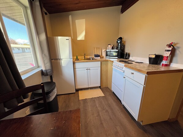 A compact kitchen with a refrigerator, microwave, stove, and sink.