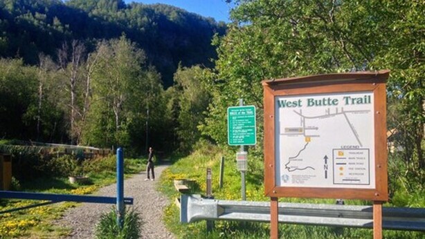 A West Butt Trail sign with a map and a person walking on a gravel path. - The Pioneer Motel (Palmer)