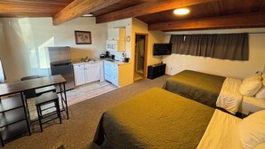 A compact room with a kitchenette, two beds, a desk, and a television. - The Pioneer Motel (Palmer)